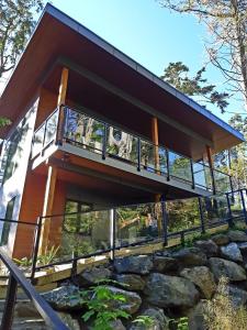 a house with a balcony on top of a rock at Storm Cove Suites in Ucluelet