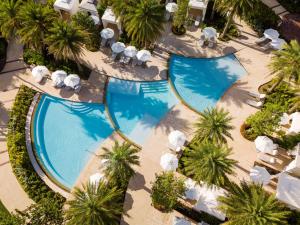 an overhead view of two swimming pools with umbrellas and palm trees at Rosewood Baha Mar in Nassau