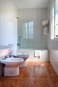 uma casa de banho com 2 WC, uma banheira e um lavatório. em Duerming San Vicente Hotel em San Vicente do Mar