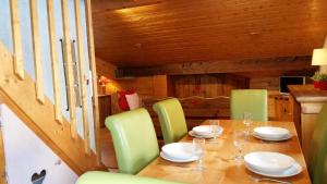 a dining room with a wooden table and green chairs at Lou Veno in Les Deux Alpes