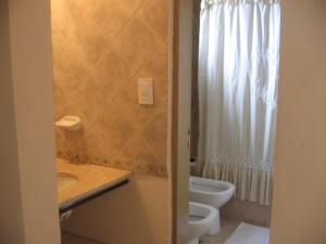 a bathroom with a toilet and a white shower curtain at Acceso Viejo Casas de Campo in La Cumbre +43 photos