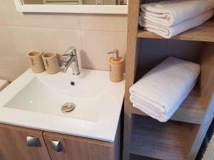 uma casa de banho com um lavatório e toalhas numa prateleira em Le Colombier Bretagne em Louannec