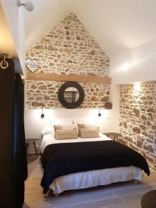 une chambre avec un grand lit avec un mur en pierre dans l'établissement Le Colombier Bretagne, à Louannec