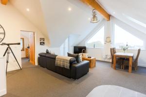 a living room with a black leather couch and a table at The Lighthouse Penthouse, Studio and Holiday Home in St Ives