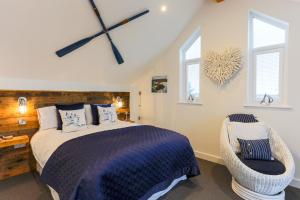 um quarto com uma cama, uma cadeira e janelas em The Lighthouse Penthouse, Studio and Holiday Home em St Ives