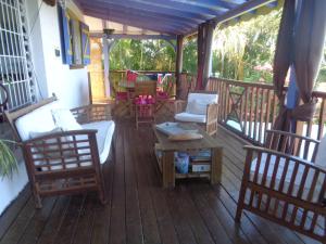 eine Veranda mit Stühlen und einem Tisch auf einer Terrasse in der Unterkunft Villa Fleur de Lune in Bouillante