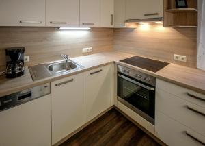 a kitchen with white cabinets and a sink and a stove at Ferienwohnung Stoff in Tux