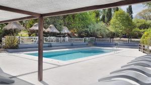 a swimming pool with chairs and an umbrella at Complejo De Cabanas Von Liss in Salsipuedes