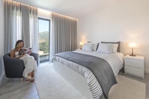 a woman sitting in a chair reading a book in a bedroom at Longra Family Villa & SPA in Barcel +37 photos