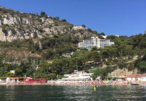 un gruppo di persone su una spiaggia con una montagna di Hotel Normandy a Cap d'Ail