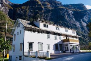 uma casa branca com uma montanha ao fundo em Gudvangen Budget Hotel em Gudvangen