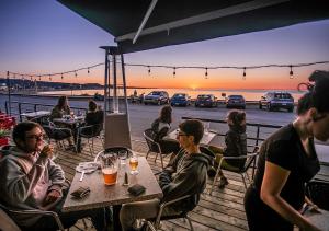 Un groupe de personnes assises à une table pour observer le coucher du soleil dans l'établissement Le Littoral Bistro Gourmand et Auberge, à Sainte-Anne-des-Monts