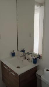 uma casa de banho com um lavatório e um espelho grande em Bosque Playa Lomas de Papudo 3 em Papudo