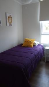 ein Bett mit einer lila Decke in einem Zimmer in der Unterkunft Bosque Playa Lomas de Papudo 3 in Papudo