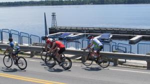 three people riding bikes down a road near the water at RépitBonka et Vélo - Péribonka in Peribonka +15 photos