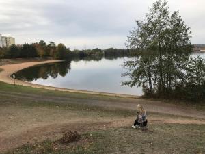 una mujer sentada en el césped cerca de un lago en Apartment Friedrich 1201, en Mainaschaff