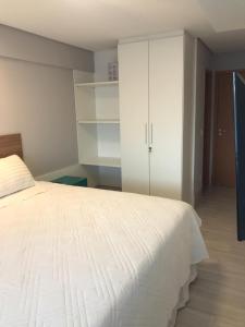 a bedroom with a white bed and white cabinets at Apto luxo, Muro alto/Porto de galinhas, Polinésia in Porto De Galinhas
