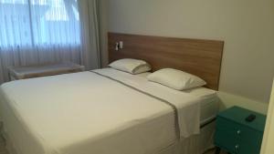 a bedroom with a large white bed with a wooden headboard at Apto luxo, Muro alto/Porto de galinhas, Polinésia in Porto De Galinhas +14 photos