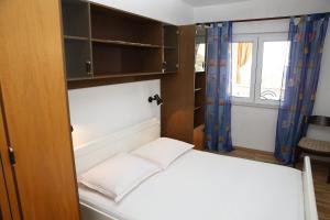 a small bedroom with a bed and a window at Apartment Ivo Ivo - relaxing&comfy in Vrgada
