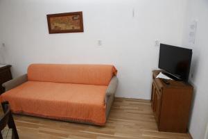 ein orangefarbenes Sofa in einem Zimmer mit einem Flachbild-TV in der Unterkunft Apartment Ivo Ivo - relaxing&comfy in Vrgada