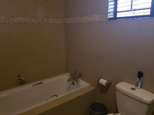 a white toilet sitting next to a bath tub at Villa Xanelle Boutique Guest House in Centurion