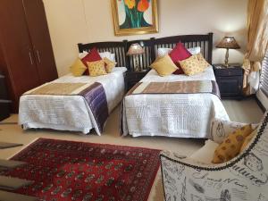 een slaapkamer met 2 bedden, een stoel en een tapijt bij Villa Xanelle Boutique Guest House in Centurion