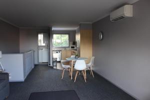 a room with a table and chairs and a kitchen at Aqualuna Apartments in Coffs Harbour