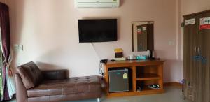 a living room with a leather couch and a television at Pawarisa Resort in Pathiu