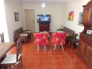 ein Wohnzimmer mit Stühlen, einem Tisch und einem TV in der Unterkunft Apto a 2 quadras da praia in Cabo Frio