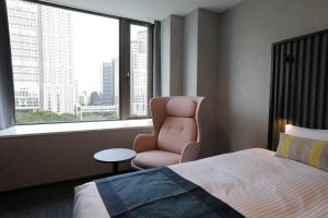 a bedroom with a bed and a chair and a window at THE KNOT TOKYO Shinjuku in Tokyo