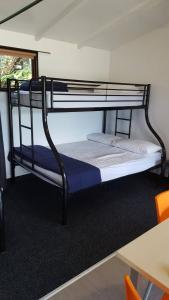 a bunk bed in a room with a desk and a table at Long Bay Motor Camp in Coromandel Town