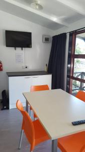 a kitchen with a white table and orange chairs at Long Bay Motor Camp in Coromandel Town