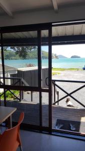 a room with a view of the beach through a window at Long Bay Motor Camp in Coromandel Town