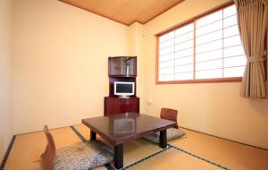 a living room with a table and a microwave at Hotel Bouenkaku in Tome