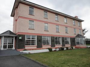 un grande edificio in mattoni con finestre bianche su un prato di Alpine Guesthouse a Dingle
