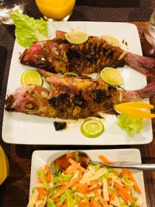 dos platos de comida con pescado y verduras en una mesa en Veli Beach Inn, en Mathiveri
