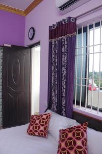 a bedroom with purple walls and a bed with two pillows at Sri Vally Residency in Puducherry