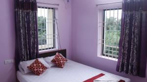 a bedroom with purple walls and a bed with two windows at Sri Vally Residency in Kālapettai