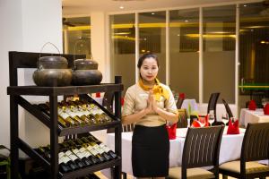 Glorious Hotel & Spa في كومبونغ ثوم: امرأة تقف أمام رف من زجاجات النبيذ