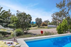 a swimming pool in front of a yard with trees at Barefoot Bungalow - Castaways Beach in Sunrise Beach