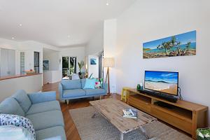 a living room with a blue couch and a tv at Barefoot Bungalow - Castaways Beach in Sunrise Beach