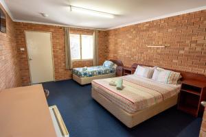a bedroom with a bed, chair and a window at Gascoyne Hotel in Carnarvon