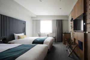 a hotel room with two beds and a flat screen tv at THE KNOT TOKYO Shinjuku in Tokyo