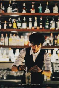 un hombre parado en un bar con una bebida en Samui Honey Cottages Beach Resort - SHA Extra Plus, en Choeng Mon Beach