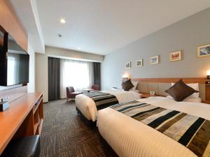 a hotel room with two beds and a flat screen tv at Hakodate Kokusai Hotel in Hakodate