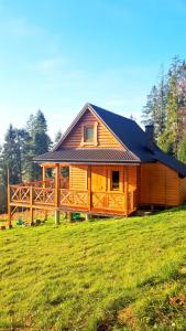 a large wooden house on a grass field at Chata w Górach-domek z Sauną in Klikuszowa