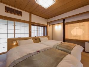 2 camas grandes en una habitación con ventanas en Okuhita Onsen Umehibiki, en Hita