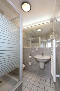 a bathroom with a sink and a toilet and a shower at LAT Hotel & Apartmenthaus Berlin in Eisenhüttenstadt