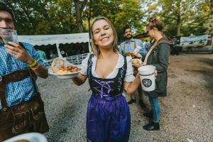 a woman holding a plate of food and a cup at Oktoberfest and Springfest Inclusive Camping in Munich