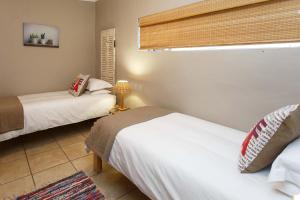 1 dormitorio con 2 camas y ventana en Hazenjacht Karoo Lifestyle - Die Melkstal, en Oudtshoorn